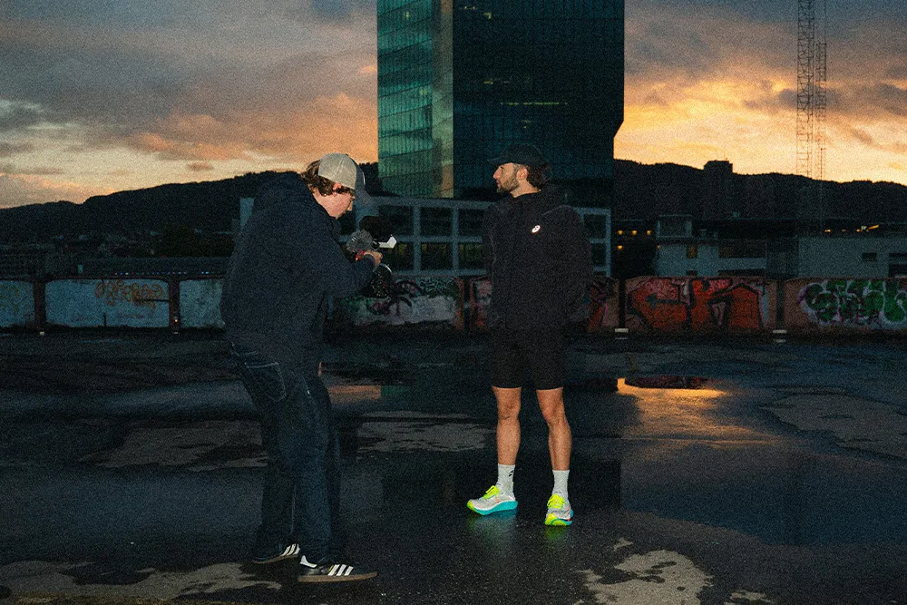 Filmmaker and runner preparing on a Zurich rooftop at sunrise